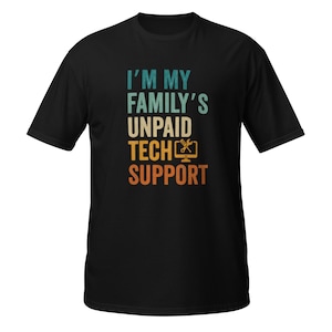 Puede incluir: Camiseta negra con el texto "I'M MY FAMILY'S UNPAID TECH SUPPORT" en verde azulado, amarillo y naranja. El diseño incluye un icono de monitor de ordenador con una llave inglesa y un destornillador. Una camiseta informal.
