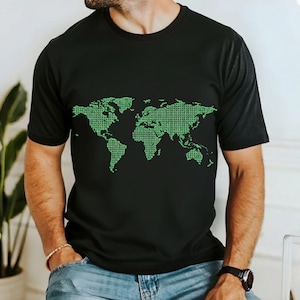 May include: Black t-shirt featuring a green world map design composed of binary code. The short-sleeved shirt is made of a soft material. The graphic is centered on the chest. The shirt is a casual wear item.