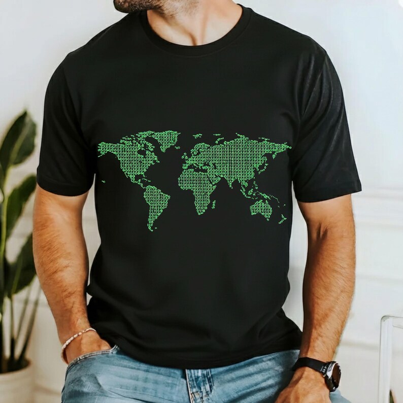 May include: Black t-shirt featuring a green world map design composed of binary code. The short-sleeved shirt is made of a soft material. The graphic is centered on the chest. The shirt is a casual wear item.