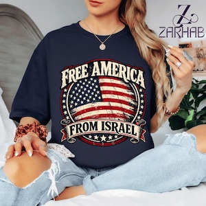 Puede incluir: Camiseta azul marino con un diseño de bandera estadounidense desgastada y el texto "FREE AMERICA FROM ISRAEL" en un emblema circular. El diseño utiliza los colores rojo, blanco y azul.