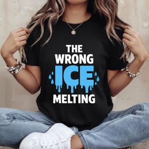 Puede incluir: Camiseta negra con el texto "THE WRONG ICE MELTING" en blanco y azul. La palabra "ICE" es azul con efecto de goteo. La camiseta es de cuello redondo y se está usando.