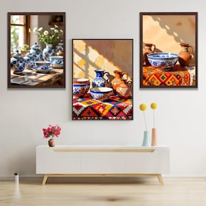 Puede incluir: Tres obras de arte enmarcadas con cerámica y vajilla. Las piezas muestran tazas de té, cuencos y jarrones con diseños azules y blancos. La obra de arte incluye un mantel estampado colorido y una mesa de madera.