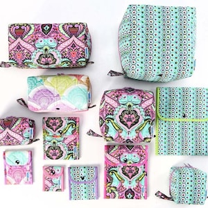 Può includere: Un assortimento di pochette e custodie in tessuto colorato di varie dimensioni. I disegni presentano motivi intricati in rosa, verde acqua e viola. Alcuni hanno una chiusura a patta, altri con cerniera. La collezione comprende varie forme e dimensioni.