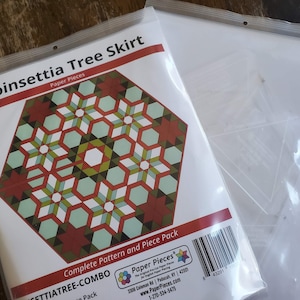 May include: A Poinsettia Tree Skirt paper piecing pattern and template set. The pattern includes a red, green, and white poinsettia design. The package includes paper pieces and acrylic templates.