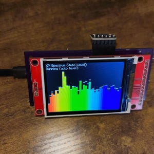 Könnte beinhalten: Ein kleines elektronisches Gerät mit einem Bildschirm, der ein farbenfrohes Spektrumdiagramm anzeigt. Das Gerät hat einen roten und violetten Rahmen mit dem Text "XP Spectrum (Auto Level) Running (auto level)". Ein schwarzes Kabel ist angeschlossen.