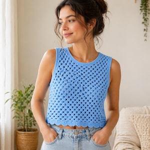 May include: A light blue crochet top with a scalloped hem. The sleeveless top has a square pattern and a round neckline. The top is paired with light wash denim jeans.