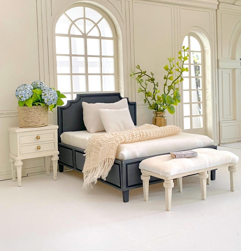 Pu&ograve; includere: Set da camera da letto in miniatura con struttura letto blu navy, biancheria da letto bianca e coperta con frange color crema. Include comodino abbinato con cesto di fiori blu e piccola panca. La stanza ha grandi finestre ad arco.