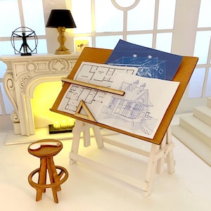 Könnte beinhalten: Ein Miniatur-Architektentisch mit Bauplänen, einem Lineal und einem Dreieck. Der Tisch ist aus Holz und hat eine weiße Basis. Ein kleiner Holzstuhl steht in der Nähe. Eine Lampe und ein Kamin befinden sich im Hintergrund.