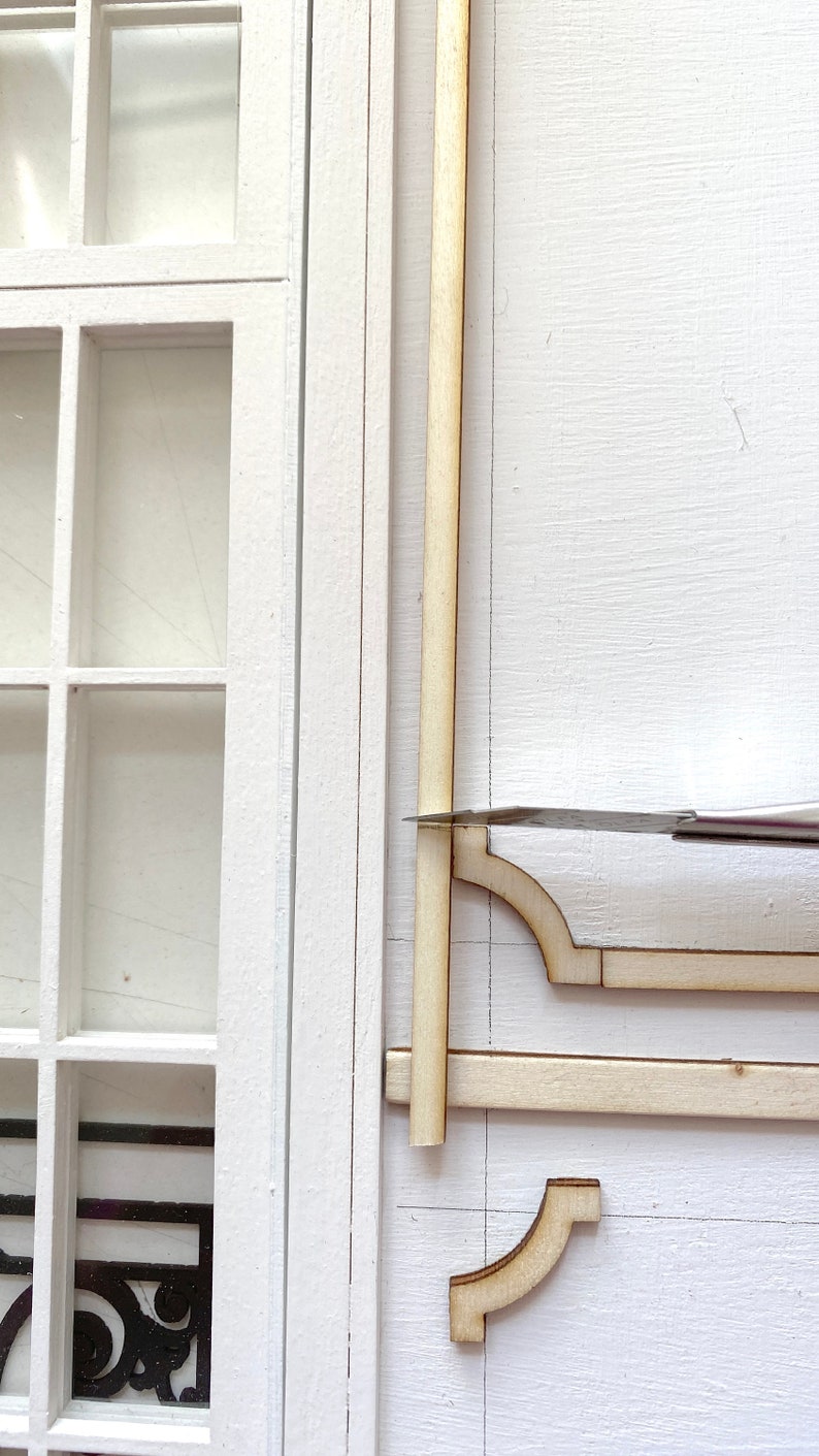 Pu&ograve; includere: Primo piano di una cornice in legno in fase di assemblaggio. La cornice &egrave; in legno chiaro e ha un design semplice. La cornice &egrave; assemblata su una superficie bianca.