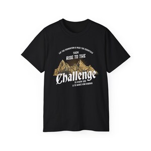 Pode incluir: Camiseta preta com um gráfico de montanhas e o texto "Lay the foundation & pack the essentials then rise to the challenge to know God & to make him known."