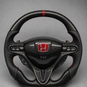 Könnte beinhalten: Ein schwarzes Lenkrad aus Kohlefaser mit einem roten Honda-Emblem in der Mitte, einem roten Streifen oben und seitlichen Griffen aus perforiertem schwarzem Leder mit roten Nähten. Das Lenkrad enthält integrierte Tasten und Schaltwippen.