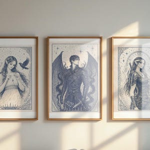 May include: Three framed art prints with gold-colored frames. Each print features a detailed blue and white illustration of a fantasy figure. The artwork includes a woman with birds, a winged figure, and a woman with a sword.