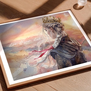 May include: Watercolor art print in a wooden frame. The artwork depicts a woman with a crown and a long braid, set against a sunset backdrop. The text "Live, Manon, Live" is written across the image. The color palette includes shades of pink, orange, and blue.