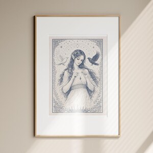 May include: Framed art print featuring a detailed illustration of a woman with long hair, adorned with flowers, and a flowing dress. Two birds flank her. The artwork is in shades of blue and white, with intricate floral and star details.