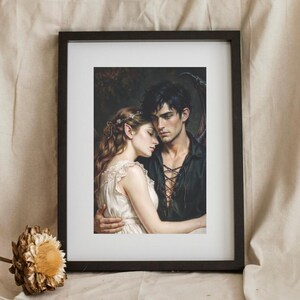 May include: A framed art print featuring a fantasy illustration of a woman with pointed ears and a white dress embracing a man with dark hair and a black lace-up shirt. The man has dark wings visible behind him. The print is in a black frame.
