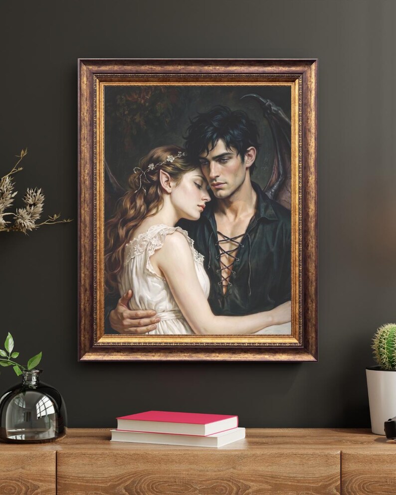May include: A framed wall art print depicting a romantic scene of a winged figure with dark hair and a black lace-up shirt embracing a person with long wavy hair, pointed ears, and a white dress, all set within an ornate, dark bronze-toned frame.