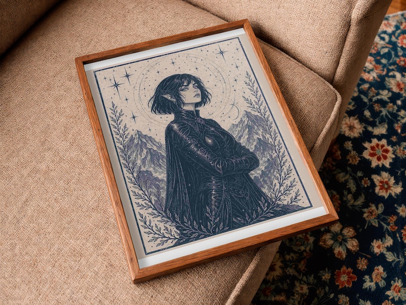 May include: Framed art print featuring a detailed illustration of a person with short hair, arms crossed, and a dark outfit. The artwork is set against a backdrop of mountains, stars, and a celestial design, framed in a wooden frame.