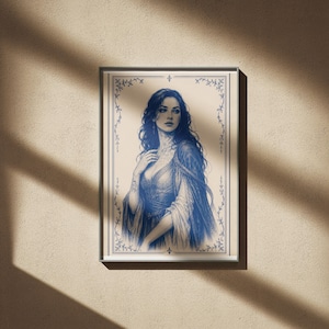 May include: A framed blue and white illustration of a woman in a flowing gown. The artwork features a detailed portrait with long, dark hair and a decorative border. The print is displayed on a beige wall, with shadows from sunlight.