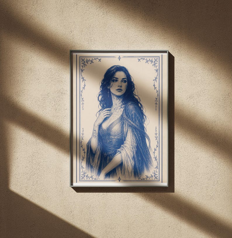 May include: A framed blue and white illustration of a woman in a flowing gown. The artwork features a detailed portrait with long, dark hair and a decorative border. The print is displayed on a beige wall, with shadows from sunlight.