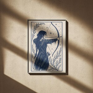 May include: Framed art print featuring a detailed illustration of a figure aiming a bow and arrow. The artwork is rendered in shades of blue and white, with a celestial background and botanical elements. The archer is depicted in a flowing gown.