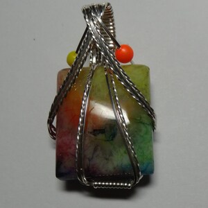May include: A colorful agate stone pendant wrapped in silver wire with orange and yellow beads.