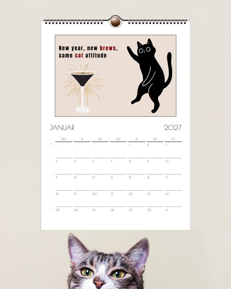 May include: A 2027 wall calendar for the month of January featuring a black cat illustration, a martini glass, and the text New year, new brews, same cat attitude. The calendar grid displays the days of the month with the header JANUAR 2027.