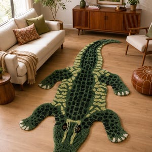Könnte beinhalten: Ein getufteter Teppich in Form eines Alligators mit einer strukturierten Oberfläche in den Farben Dunkelgrün, Oliv und Hellgrün. Der Teppich zeigt ein detailliertes Schuppenmuster auf dem Rücken, einen langen, geschwungenen Schwanz und vier Gliedmaßen.