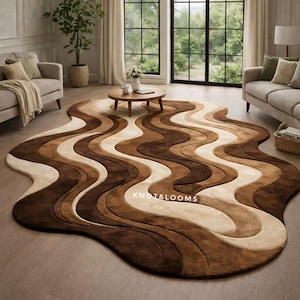 May include: A brown, beige, and cream-coloured area rug with a wavy design. The rug is on a hardwood floor in a living room setting. The rug has the text "KNOT&LOOMS" on it.