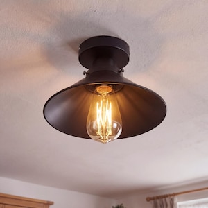 Könnte beinhalten: Eine schwarze Deckenleuchte im Industriestil mit einem nach unten gerichteten, konischen Schirm. Sie verfügt über eine Vintage-Edison-Glühbirne, die ein warmes Licht ausstrahlt. Die Leuchte ist an einer weißen Decke montiert, passend für die Inneneinrichtung. Der Durchmesser beträgt ca. 30 cm.