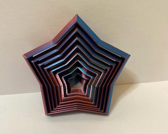 May include: A set of nested star-shaped cookie cutters. The cutters are arranged in a gradient of colors, transitioning from red to blue. The set includes multiple sizes, perfect for baking or crafting.