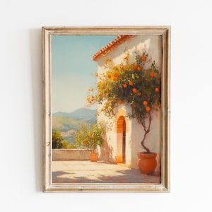 Puede incluir: Impresión vintage enmarcada de una escena mediterránea. Un edificio de estuco blanco con una puerta arqueada está adornado con naranjos con frutos maduros. La obra de arte se encuentra sobre un fondo de colinas y un cielo azul claro.