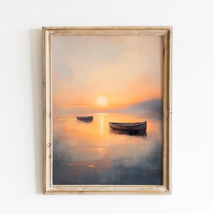 May include: A framed landscape painting depicts a serene sunset over a calm body of water. Two boats float on the water, reflecting the warm orange and yellow hues of the sky. The artwork is encased in a distressed, light-colored wooden frame.