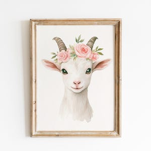 Könnte beinhalten: Aquarell-Illustration einer weißen Ziege mit einem Blumenkranz aus rosa Rosen und grünen Blättern. Die Ziege hat braune Hörner und grüne Augen. Das Kunstwerk ist in einem hellbraunen Holzrahmen gerahmt.