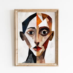 May include: Abstract portrait art print in a wooden frame. The artwork features a geometric face with a split design, using shades of brown, orange, black, and white. The subject has red lips and dark eyes, creating a striking visual.