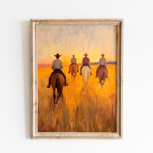 May include: Oil painting of five cowboys on horseback riding through a field at sunset. The artwork features warm tones of yellow, orange, and brown, with the cowboys silhouetted against the sky. The painting is framed in a distressed, light-colored wooden frame.