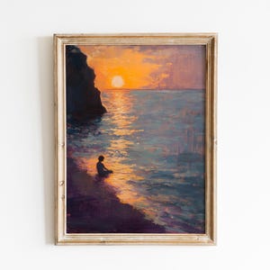 May include: Framed oil painting of a sunset over the ocean. The artwork depicts a silhouetted figure sitting on the shore, with the sun reflecting on the water. The painting is in a gold-toned frame.