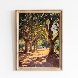 May include: A framed landscape painting depicts a sunlit path through a grove of trees. The artwork features a warm color palette with shadows cast across the path. The trees have lush green foliage, and the frame is a light, neutral color.