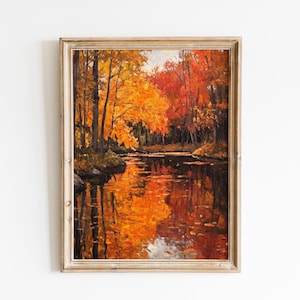Könnte beinhalten: Gerahmtes Landschaftsgemälde, das eine ruhige Herbstszene darstellt. Das Kunstwerk zeigt einen Fluss, der die leuchtenden Farben des Herbstlaubes widerspiegelt, mit Farbtönen von Orange, Rot und Gelb. Das Gemälde ist in einem rustikalen, hellen Holzrahmen eingefasst.