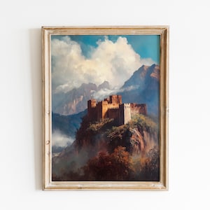 Puede incluir: Pintura de paisaje vintage enmarcada de un castillo en la cima de una montaña, con un cielo nublado y una cordillera al fondo. El castillo es de color marrón cálido y el marco es de color beige claro.