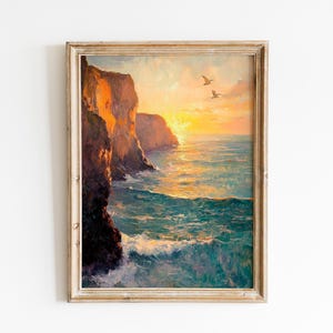 Puede incluir: Pintura enmarcada de un paisaje costero al atardecer. La obra presenta acantilados en tonos naranja y marrón, un mar turquesa y dos pájaros en vuelo. La pintura está en un marco de madera clara y envejecida, evocando la belleza natural.