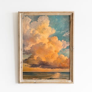 May include: A framed landscape painting depicts a dramatic sky with large, fluffy clouds in shades of orange, yellow, and blue. The artwork features a serene ocean scene at the bottom, with a golden light reflecting on the water.