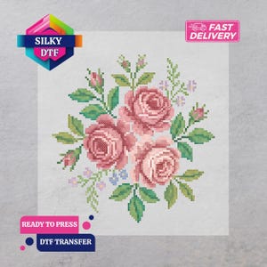 May include: DTF transfer featuring a cross-stitch design of pink roses, green leaves, and small blue and purple flowers. The words "SILKY DTF" and "READY TO PRESS DTF TRANSFER" are visible.