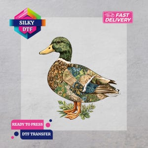 May include: A detailed illustration of a duck with a green head, yellow beak, and patchwork-style body. The duck is standing on a bed of green leaves. The image includes the text "SILKY DTF", "FAST DELIVERY", "READY TO PRESS", and "DTF TRANSFER".