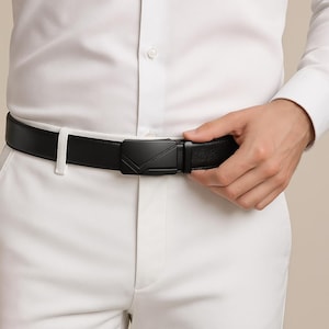 Puede incluir: Un cintur&oacute;n de cuero negro con una hebilla geom&eacute;trica. El cintur&oacute;n se lleva con pantalones blancos y una camisa blanca abotonada. La hebilla tiene un acabado negro mate.