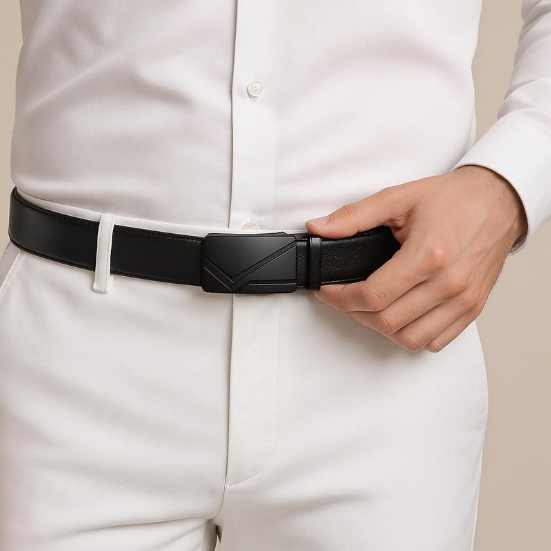 Puede incluir: Un cintur&oacute;n de cuero negro con una hebilla geom&eacute;trica. El cintur&oacute;n se lleva con pantalones blancos y una camisa blanca abotonada. La hebilla tiene un acabado negro mate.