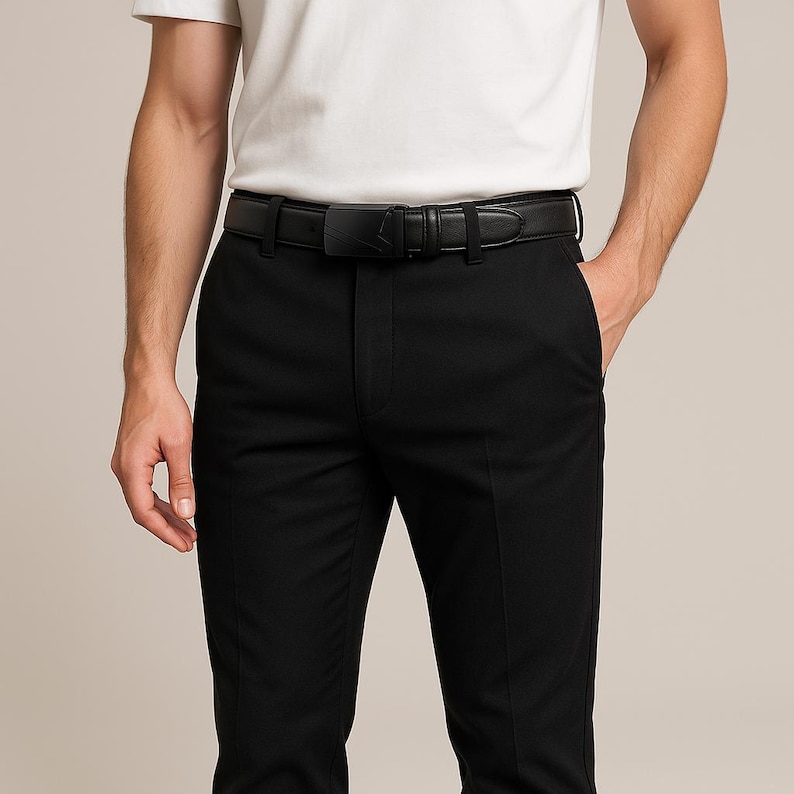 Puede incluir: Cintur&oacute;n de cuero negro con un dise&ntilde;o de hebilla &uacute;nico, usado con pantalones negros. Un accesorio cl&aacute;sico para vestimenta formal o de negocios. La hebilla tiene una forma distintiva.