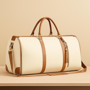 May include: Cream-colored duffel bag with brown leather accents. Features include a top handle, shoulder strap, and decorative tassel. The bag is designed for travel and has a classic, elegant style.