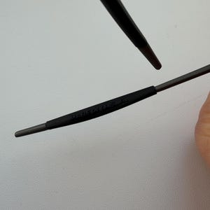 May include: Close-up of a pair of dark gray eyeglasses. The text "MADE IN U.S.A." is printed on the temple arm. The frame is a dark gray color.