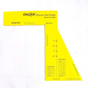 May include: A yellow plastic blouse dart scale with the text "deepak Blouse Dart Scale" and measurements in inches. The scale includes markings for hook side, mid-point, and dart width difference.