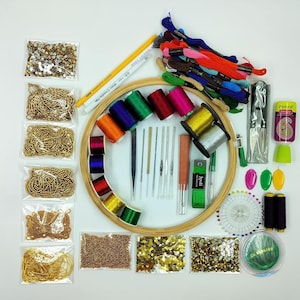 May include: A craft kit featuring a wooden embroidery hoop, colourful embroidery floss, needles, scissors, and various beads and sequins. The kit includes a measuring tape, thread, and a needle threader. The items are arranged on a white surface.